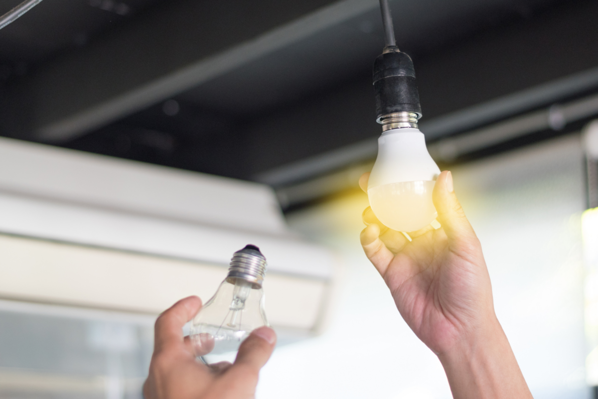 An electrician from Streb Electric replacing an incandescent light bulb with an LED light bulb because of the greater benefits of using LED bulbs.