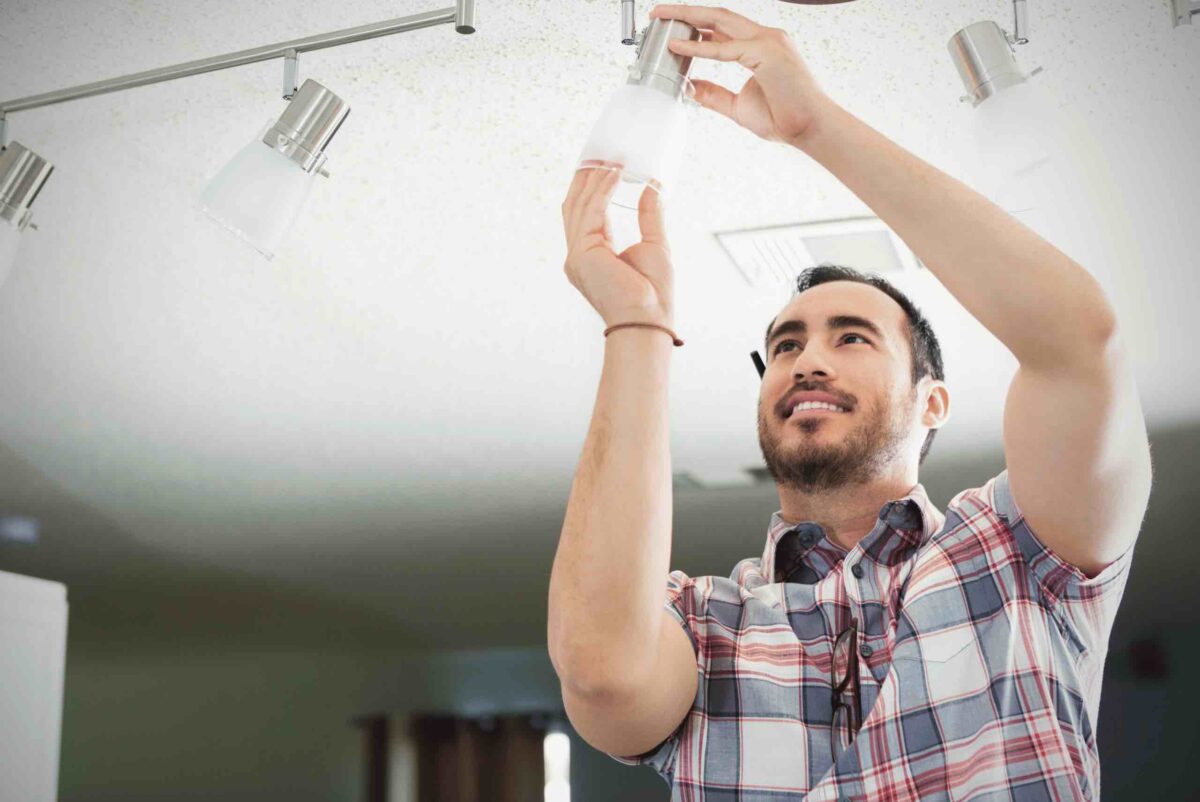 A man inspecting a residential light fixture to represent why you may have failing light fixtures and how to fix them
